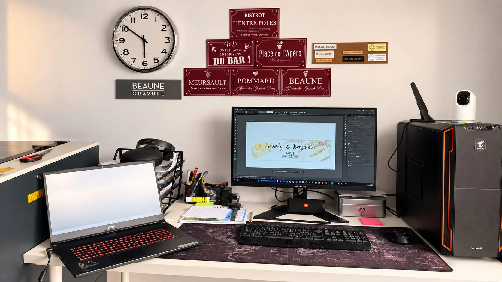 Le poste de création du studio : un logiciel de dessin vectoriel affiche un projet de gravure en cours, devant le mur des pièces déjà réalisées