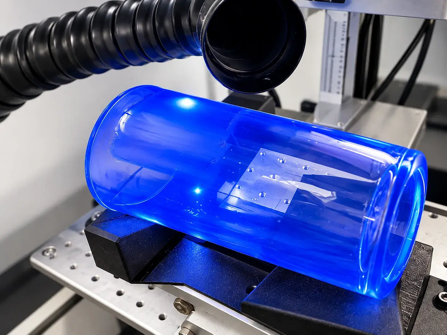 Pièce cylindrique en verre teinté bleu en cours de marquage sur l’axe rotatif du laser